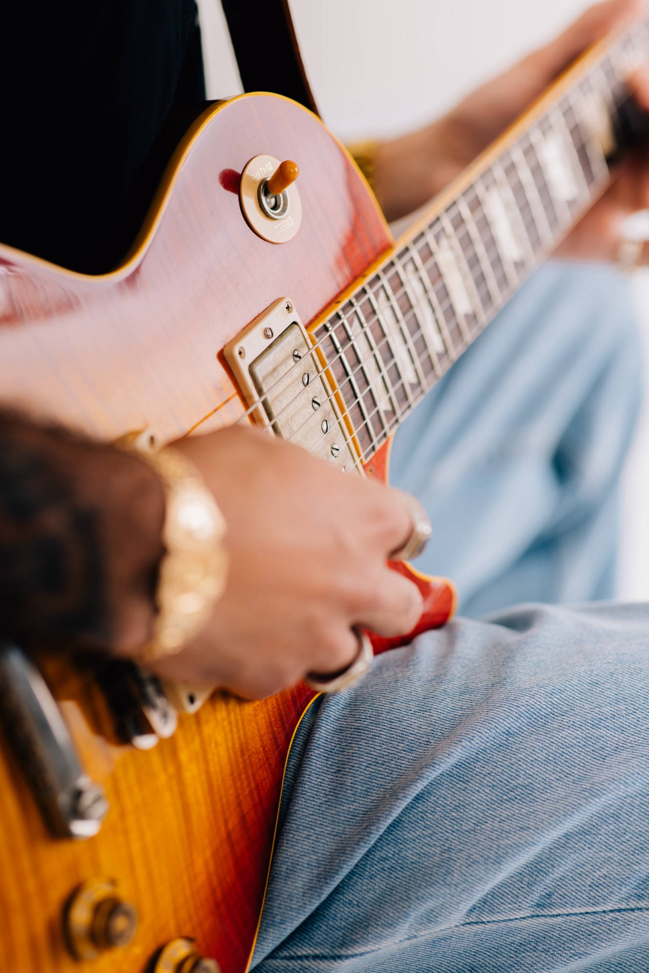 Close-up of hands strumming a sunburst Les Paul guitar