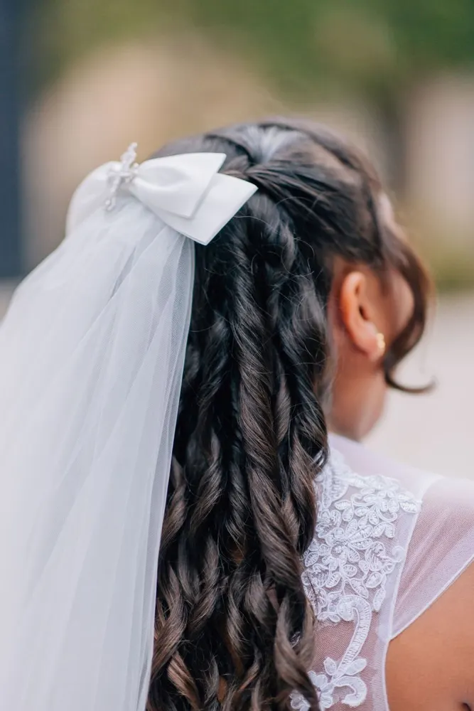 Detail of a communion veil and braided hair from behind