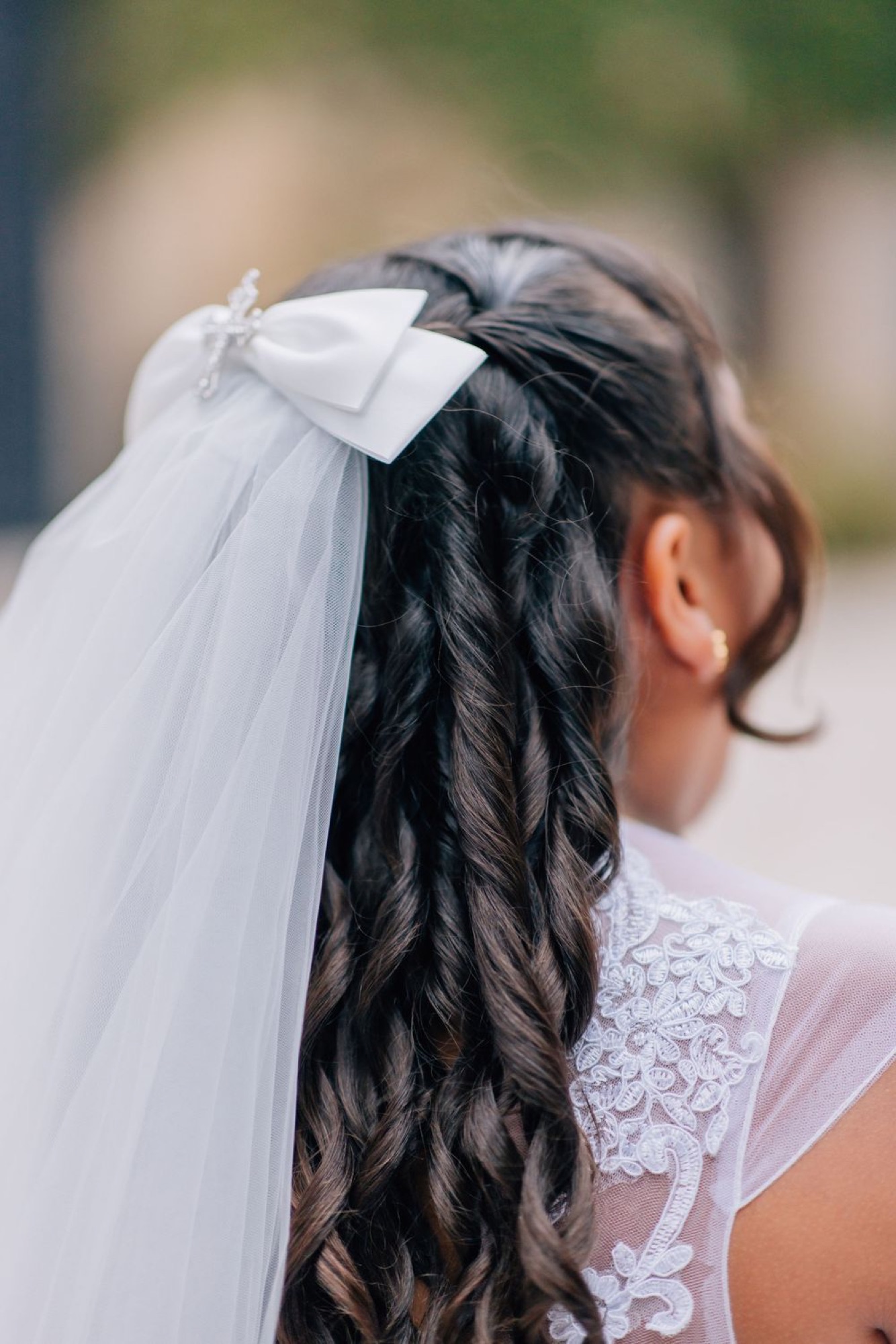 Detail of a communion veil and braided hair from behind