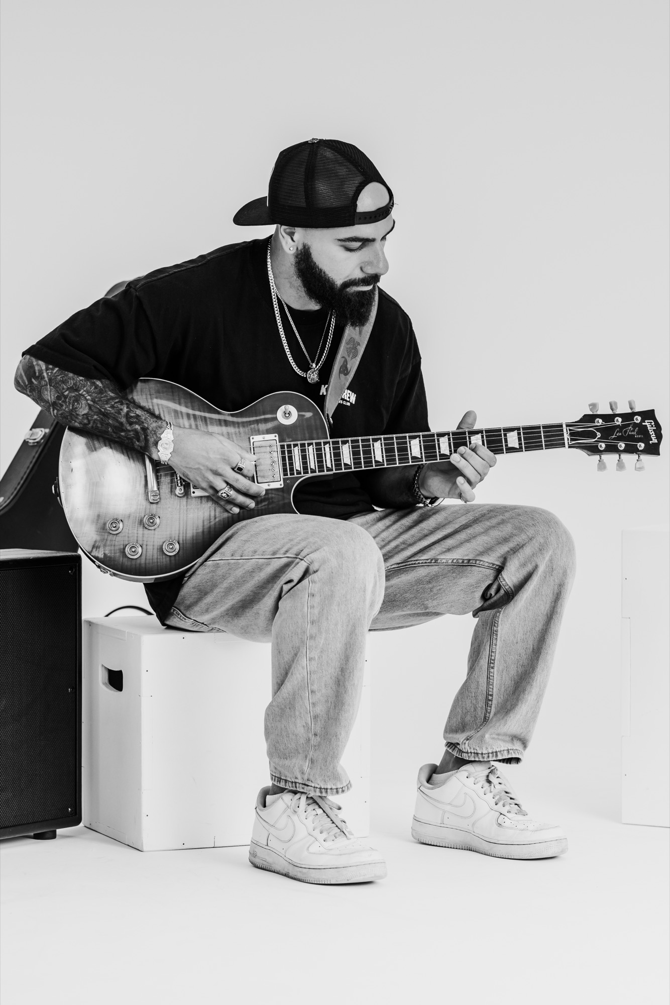 Black and white portrait of a bearded musician playing a Les Paul guitar in the studio
