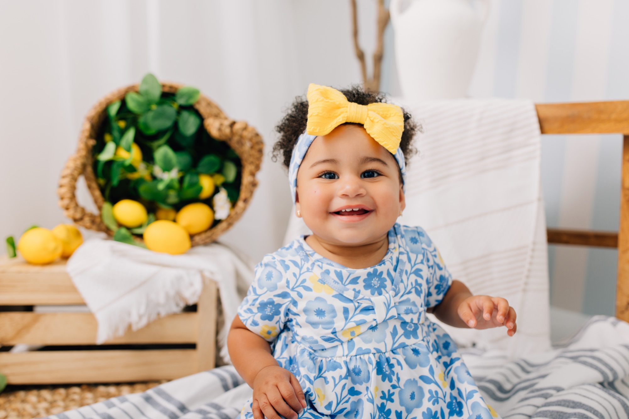 Laughing baby girl in a blue floral dress on a lemonade-themed studio set