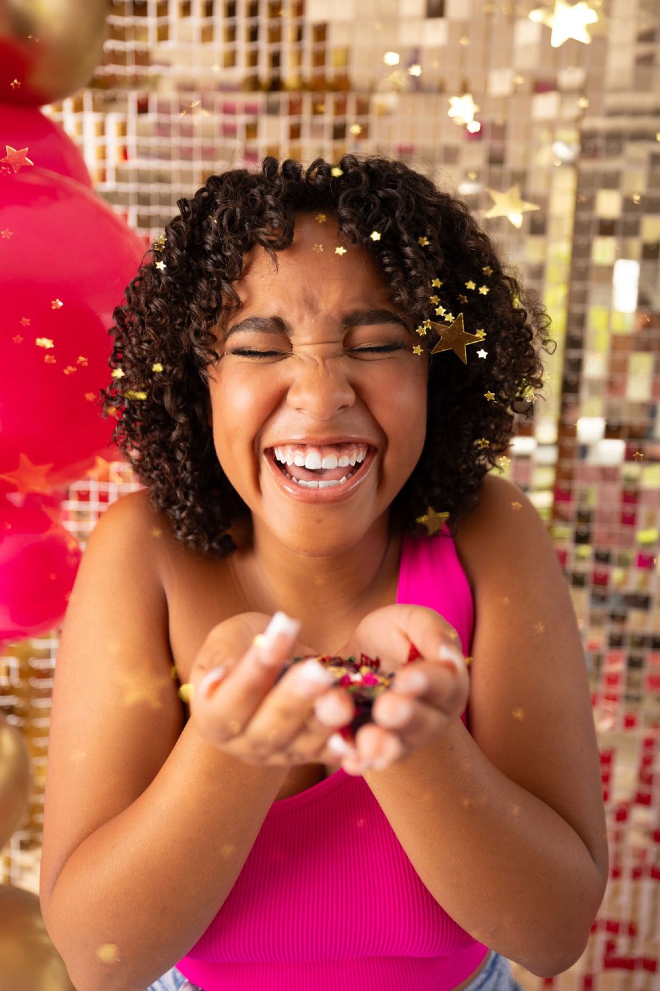Teen laughing joyfully as gold confetti falls around her
