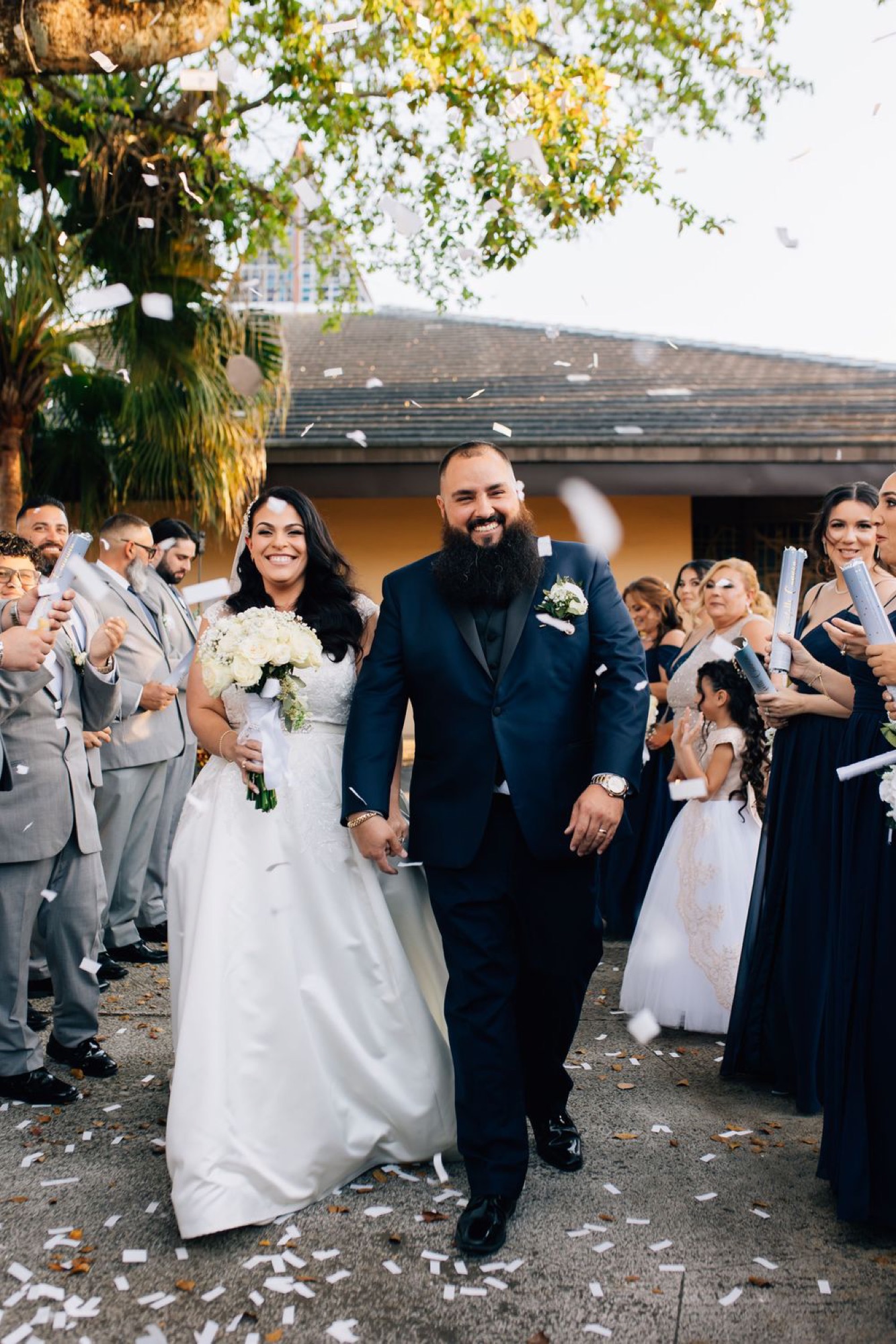 Newlyweds walking through a confetti-filled recessional surrounded by cheering guests