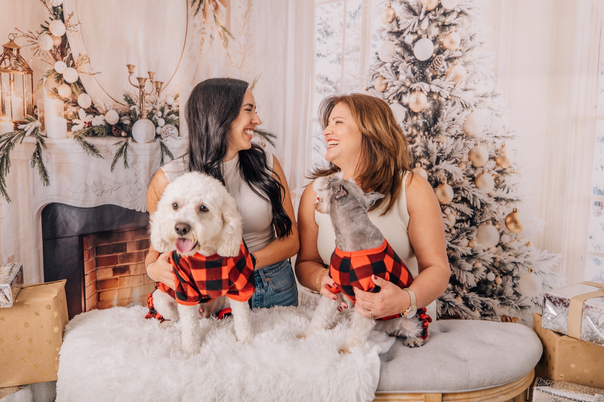 Mother and daughter laughing with their dogs in matching plaid pajamas on a Christmas mini set