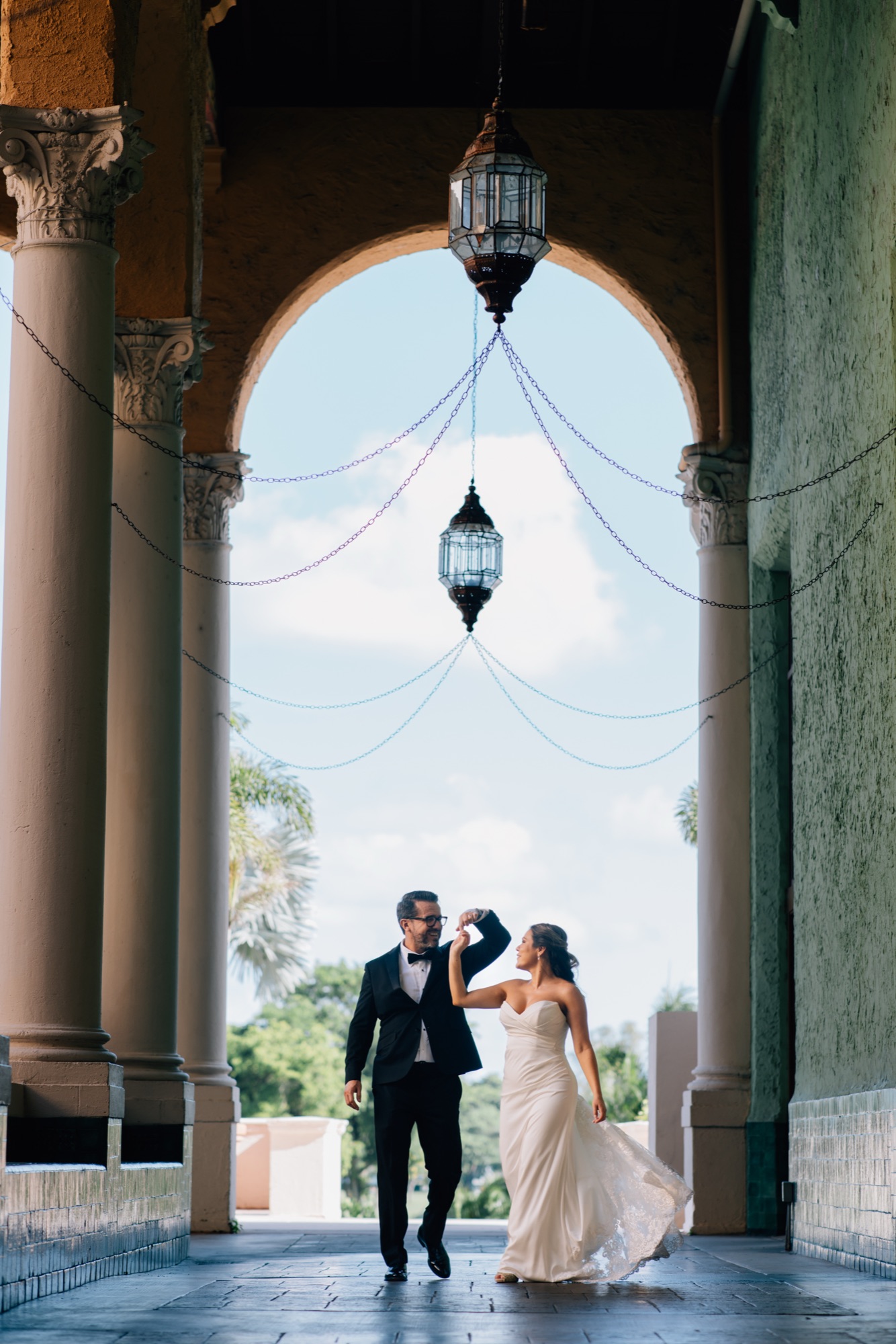 Bride and groom dancing beneath hanging lanterns in a Mediterranean archway